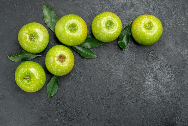 Vista superior de cerca manzanas verdes seis manzanas verdes con hojas sobre la mesa oscura