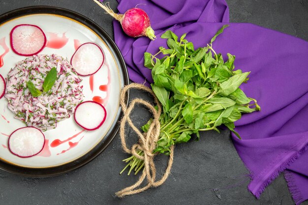 Vista superior de cerca un plato apetitoso con salsa de rábano y hierbas en el plato junto al mantel morado