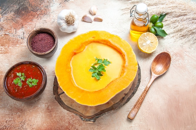 Vista superior de cerca sopa aceite de ajo cuchara de limón salsa especias sopa de calabaza con hierbas