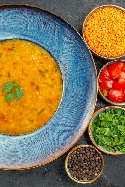 Vista superior de cerca sopa de lentejas tazón azul de sopa de lentejas tomates especias pimienta negra hierbas