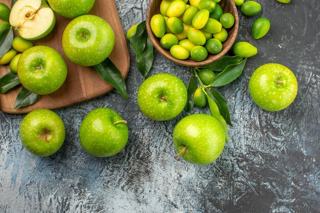 Vista superior de cerca tazón de manzanas de frutas cítricas tablero del apetitoso cuchillo de manzanas verdes