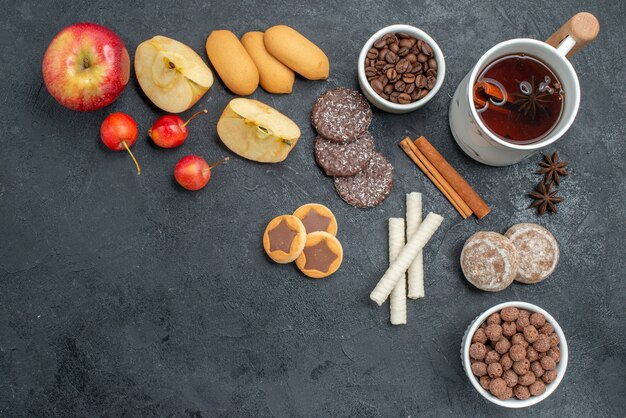 Vista superior de cerca té manzanas cerezas galletas una taza de té granos de café de anís estrellado