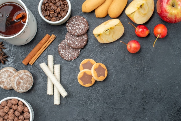 Vista superior de cerca té una taza de té anís estrellado granos de café manzanas cerezas galletas