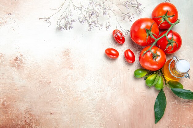 Vista superior de cerca tomates tomates con pedicelos cítricos con hojas botella de aceite