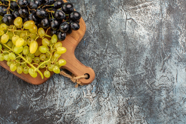 Foto gratuito vista superior de cerca las uvas las apetitosas uvas verdes y negras en el tablero de la cocina