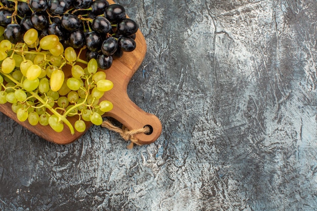Vista superior de cerca las uvas las apetitosas uvas verdes y negras en el tablero de la cocina