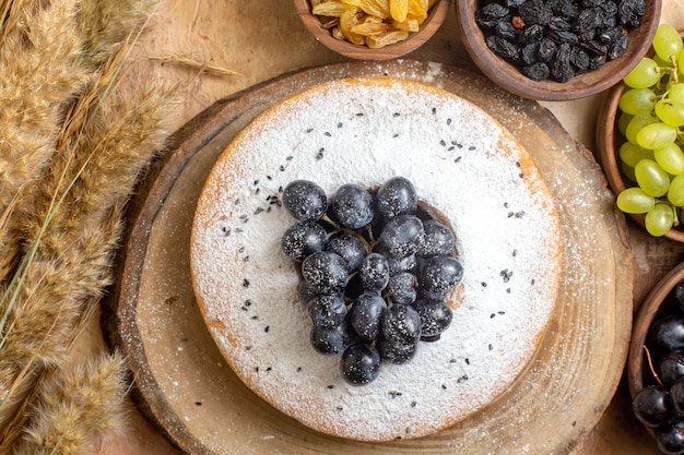 Foto gratuita vista superior de cerca de uvas un pastel con uvas tazones de uvas negras y verdes pasas espiguillas