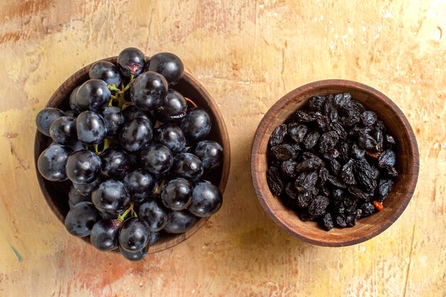 Vista superior de cerca uvas tazones de pasas y uvas negras sobre la mesa