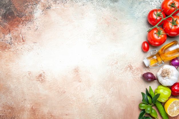 Vista superior de cerca verduras tomates con pedicelos ajo pimientos aceite de limón cebolla