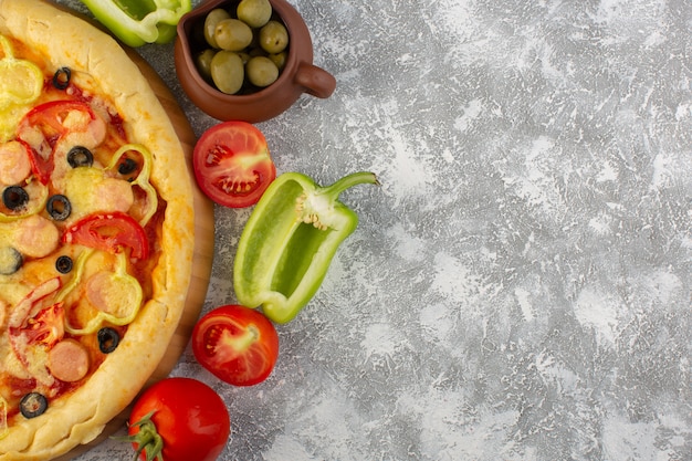 Vista superior cercana deliciosa pizza con queso con aceitunas, salchichas y tomates en el escritorio gris comida rápida comida de masa italiana