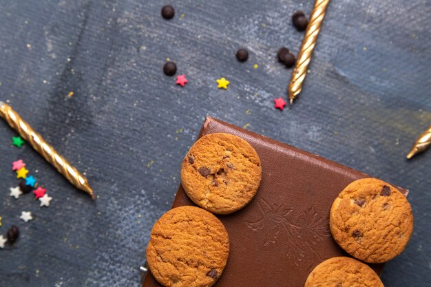 Vista superior cercana deliciosas galletas de chocolate en la caja marrón con velas en el fondo gris oscuro galleta galleta dulce