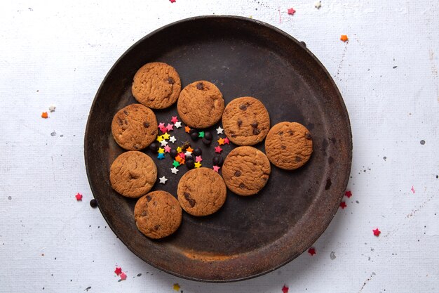 Vista superior cercana deliciosas galletas de chocolate dentro de la placa redonda oscura en el escritorio blanco galleta galleta té dulce