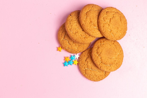 Vista superior cercana deliciosas galletas dulces horneadas forradas en el fondo rosa