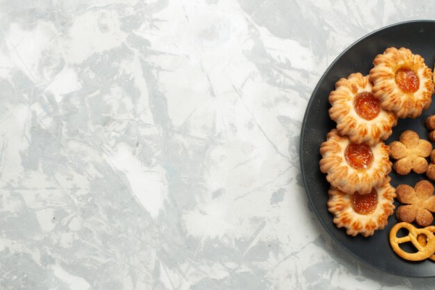 Vista superior cercana deliciosas galletas con galletas saladas y patatas fritas dentro de la placa en el escritorio de color blanco claro