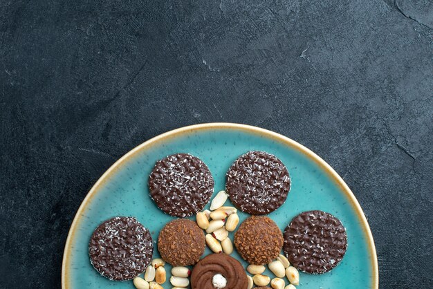 Vista superior cercana de diferentes galletas de chocolate con nueces en la superficie de color gris oscuro