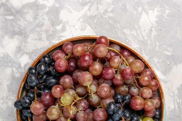 Vista superior cercana diferentes uvas jugosas frutas amargas suaves en la luz de escritorio blanco fruta fresca jugo suave vino