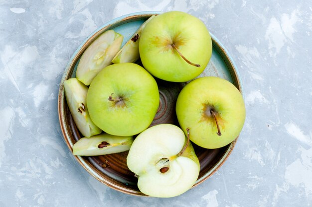 Vista superior cercana de manzanas verdes frescas en rodajas y frutas enteras en la superficie de la luz fruta fresca vitamina madura suave comida