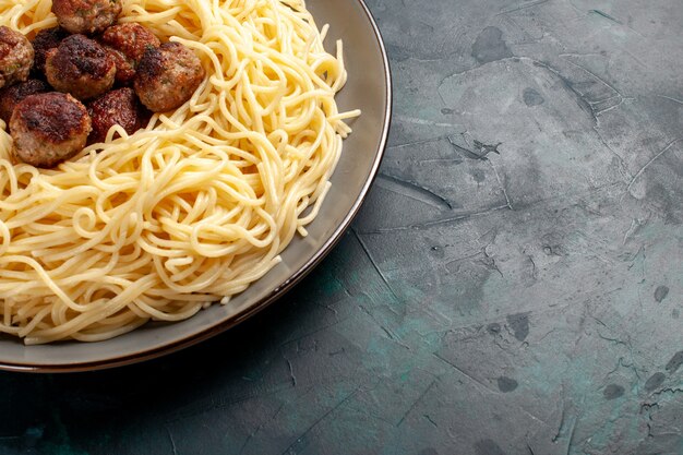 Vista superior cercana pasta italiana cocida con albóndigas en la superficie azul oscuro