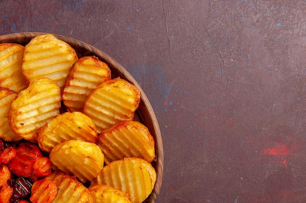 Vista superior cercana patatas al horno con verduras cocidas en un espacio oscuro