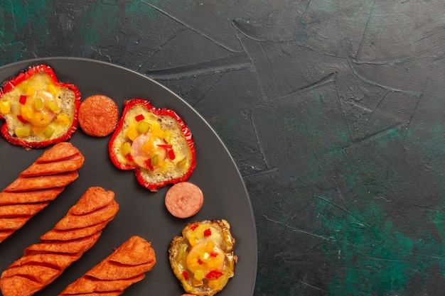 Foto gratuita vista superior cercana de pimientos cocidos con salchichas fritas dentro de la placa en la superficie de color verde oscuro