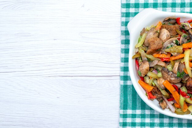 Vista superior cercana del plato de carne en rodajas con verduras cocidas dentro de la placa a la luz