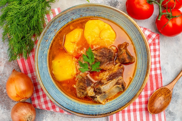 Vista superior cercana toalla de cocina de sopa bozbash casera un manojo de eneldo tomates cebollas cuchara de madera