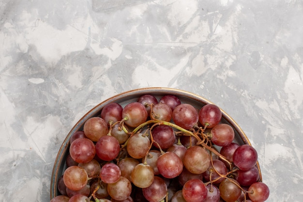 Vista superior cercana uvas rojas frescas jugosas frutas dulces suaves en el escritorio de color blanco claro fruta fresca jugo suave vino
