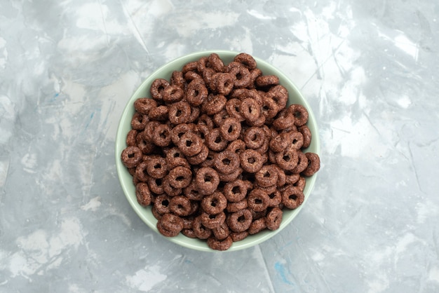 Vista superior de cereales de chocolate dentro de la placa verde en azul, cacao desayuno alimentos cereales salud