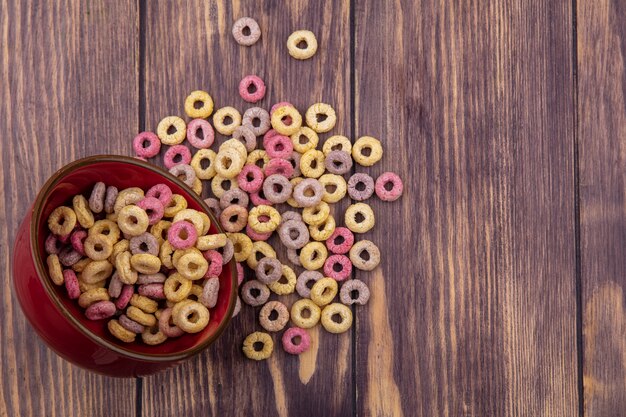 Vista superior de cereales multicolores y de asa en un tazón rojo con cereales aislados en una superficie de madera