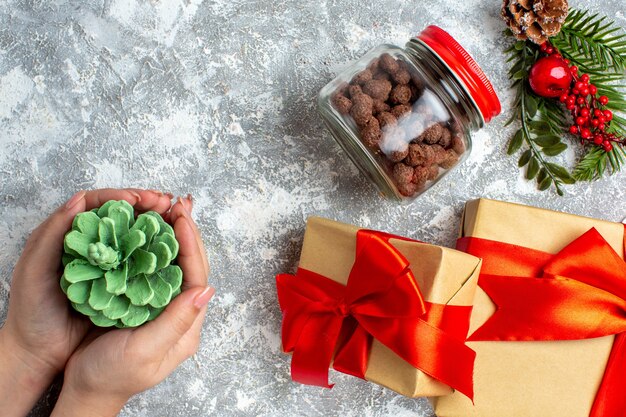 Vista superior de cereales de regalos de Navidad en frasco cono verde en mano femenina en mesa gris