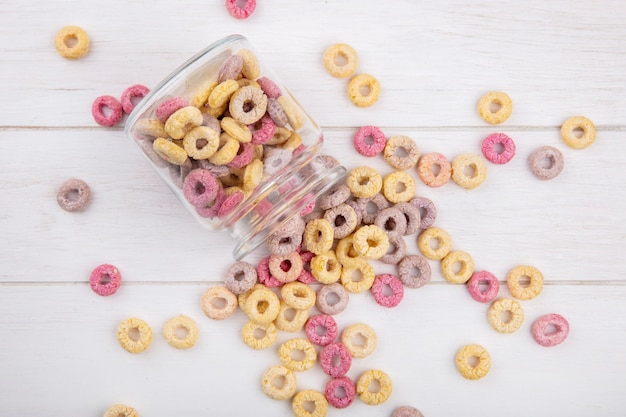 Vista superior de cereales sanos y multicolores en un frasco de vidrio con cereales aislados en superficie de madera blanca