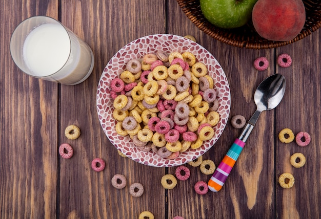 Vista superior de cereales en un tazón con una cuchara con un vaso de leche en madera