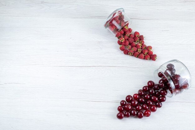 Vista superior de cerezas ácidas frescas con frambuesas a la luz, jugo suave de bayas de frutas