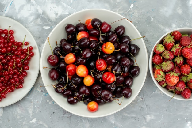 Una vista superior de cerezas y fresas con arándanos dentro de la placa blanca.