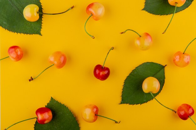 Vista superior de cerezas lluviosas maduras frescas con hojas verdes en amarillo