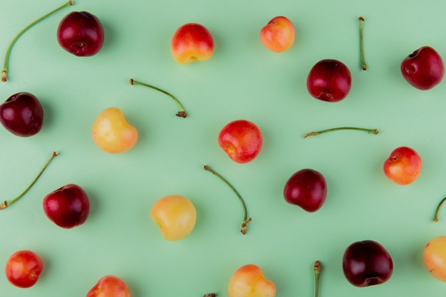 Vista superior de cerezas maduras más lluviosas y cerezas rojas aisladas en color menta