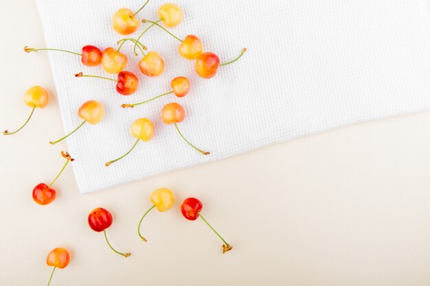 Vista superior de cerezas sobre tela blanca y superficie blanca con espacio de copia