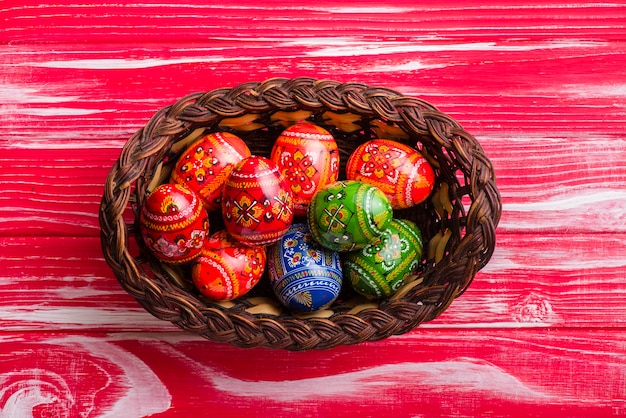 Vista superior de cesta con huevos de pascua sobre superficie de madera