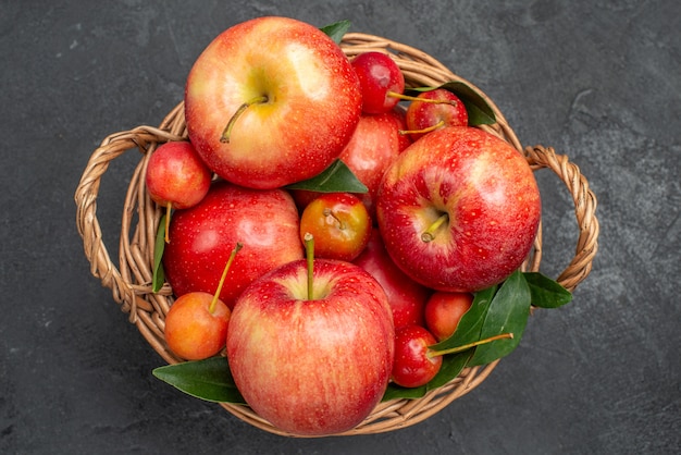 Vista superior de la cesta de madera de frutas con cerezas y manzanas