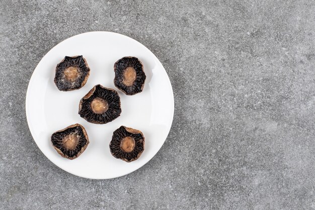 Foto gratuita vista superior de champiñones cocidos en plato blanco sobre superficie gris