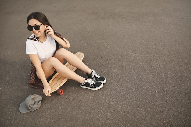 Foto gratuita vista superior chica hipster despreocupada en gafas de sol, snapback en el suelo