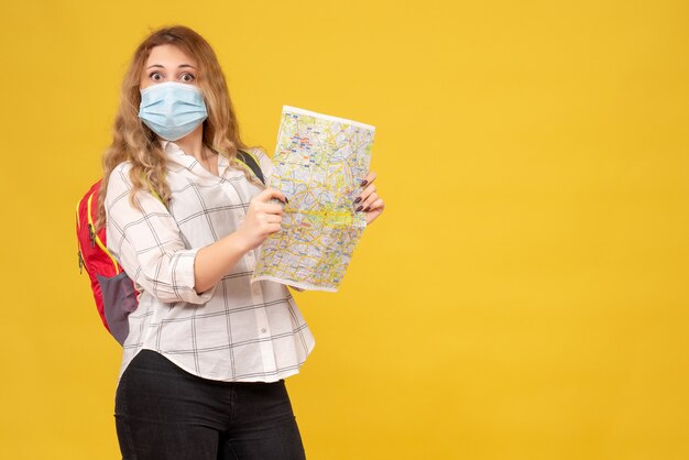 Vista superior de la chica que viaja confiada con su máscara y mochila con mapa en amarillo