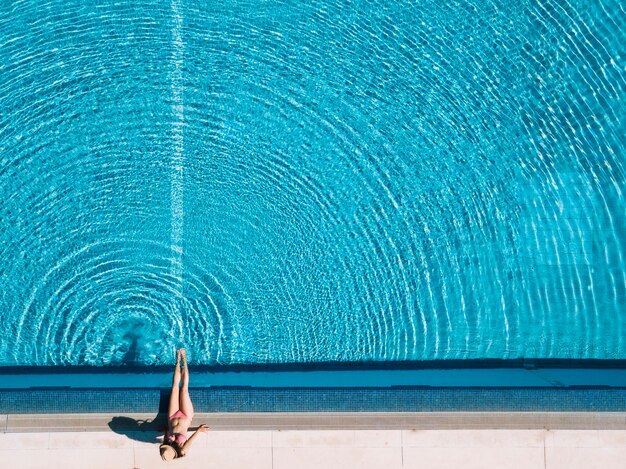 Vista superior de chica relajando al lado de piscina
