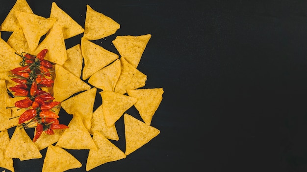 Foto gratuita vista superior de chips de nachos mexicanos calientes con chiles rojos sobre fondo negro