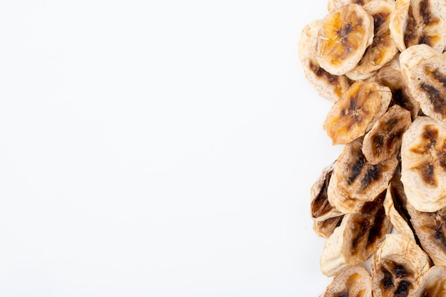 Foto gratuita vista superior de chips de plátano secos dispuestos en el lateral sobre fondo blanco con espacio de copia