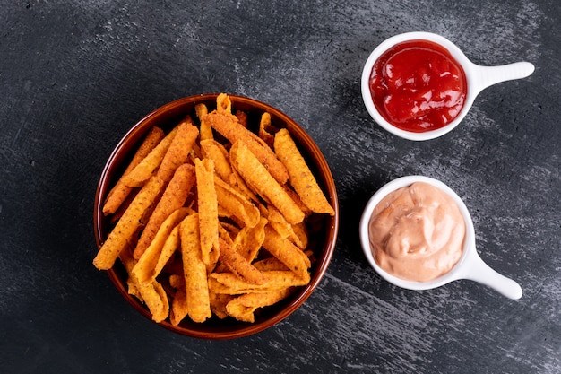 Vista superior chips con salsas en cuencos en piedra negra