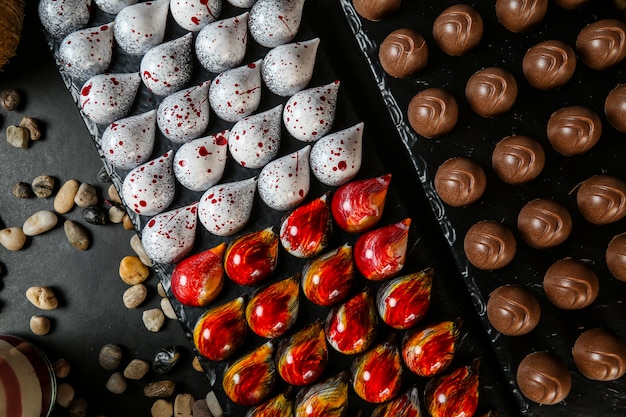 Foto gratuita vista superior de chocolates decorativos de colores en un stand con piedras sobre un fondo negro