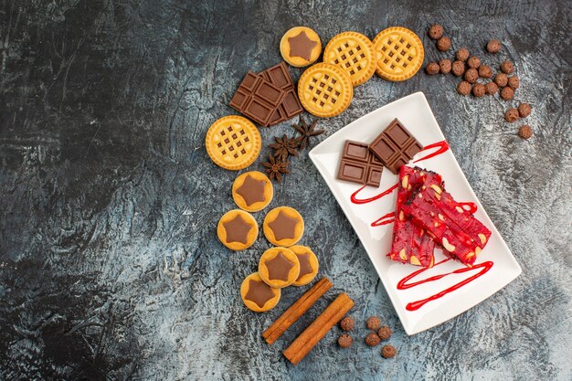 Vista superior de chocolates en plato blanco con un montón de deliciosos dulces en suelo gris