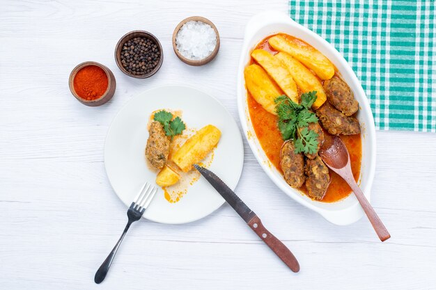 Vista superior de chuletas de carne cocida con salsa de patatas y condimentos verdes a la luz, comida comida carne vegetal pimienta