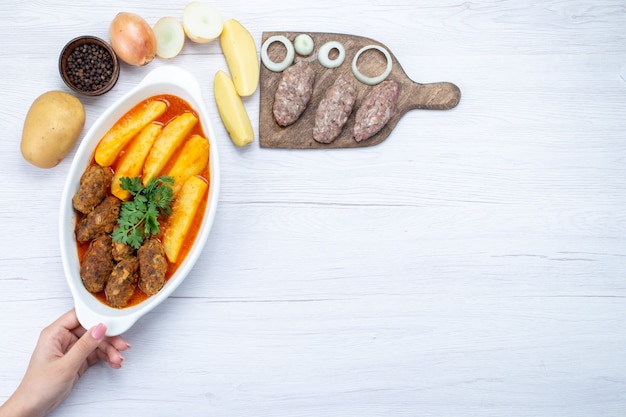 Vista superior de chuletas de carne cocida con salsa de patatas y verde junto con carne cruda a la luz, comida carne vegetal